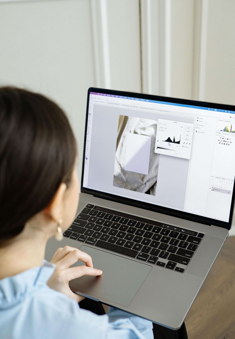 A woman designing in Photoshop on her laptop—representing the fast, focused creative support of a Design Day Intensive.