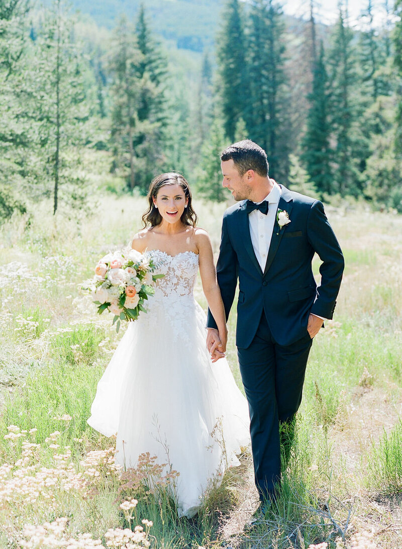 Bride and groom holding hands in a field