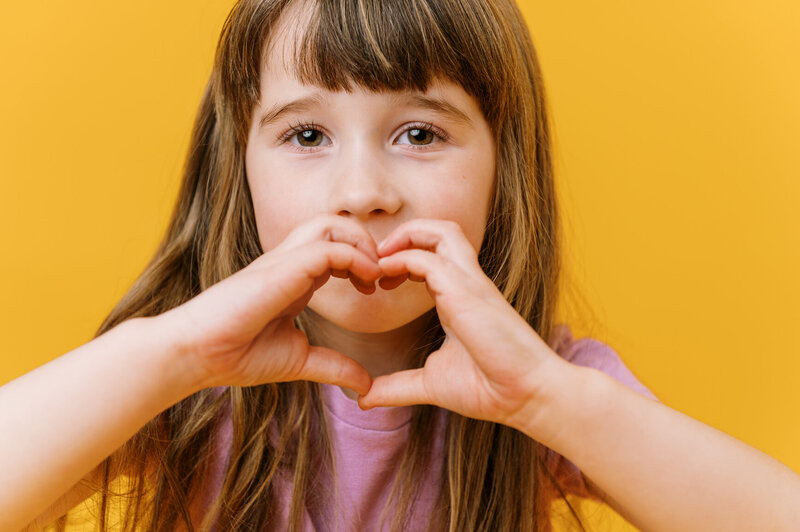 Happy child making heart with hands