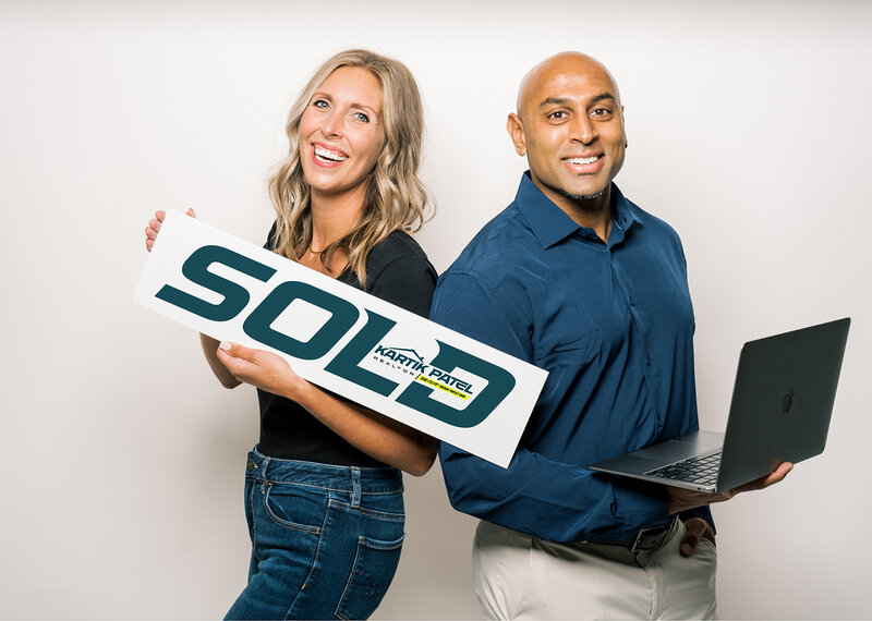 Two people holding a sold sign for Kartik Patel Real Estate agent design by Amanda Newman Design in Paducah, Kentucky