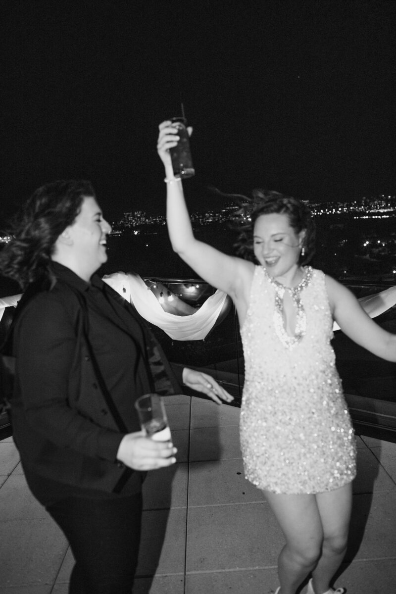 lesbian brides on a terrace at night in DC celebrating and drinking