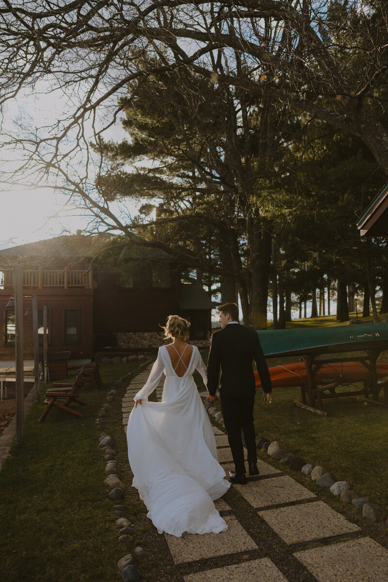 Man and woman walking away towards cabin in wedding attire