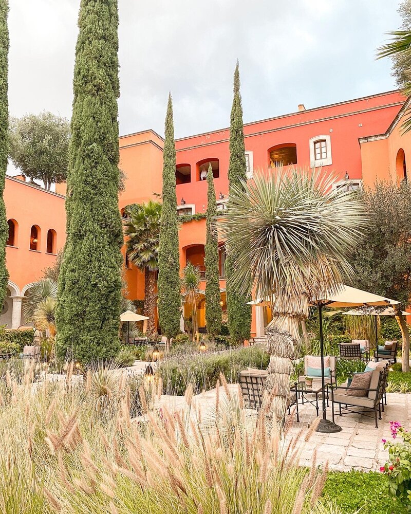 Courtyard garden and colorful adobe architecture at Rosewood San Miguel de Allende, a luxury Mexico wedding venue surrounded by cacti and lush greenery.