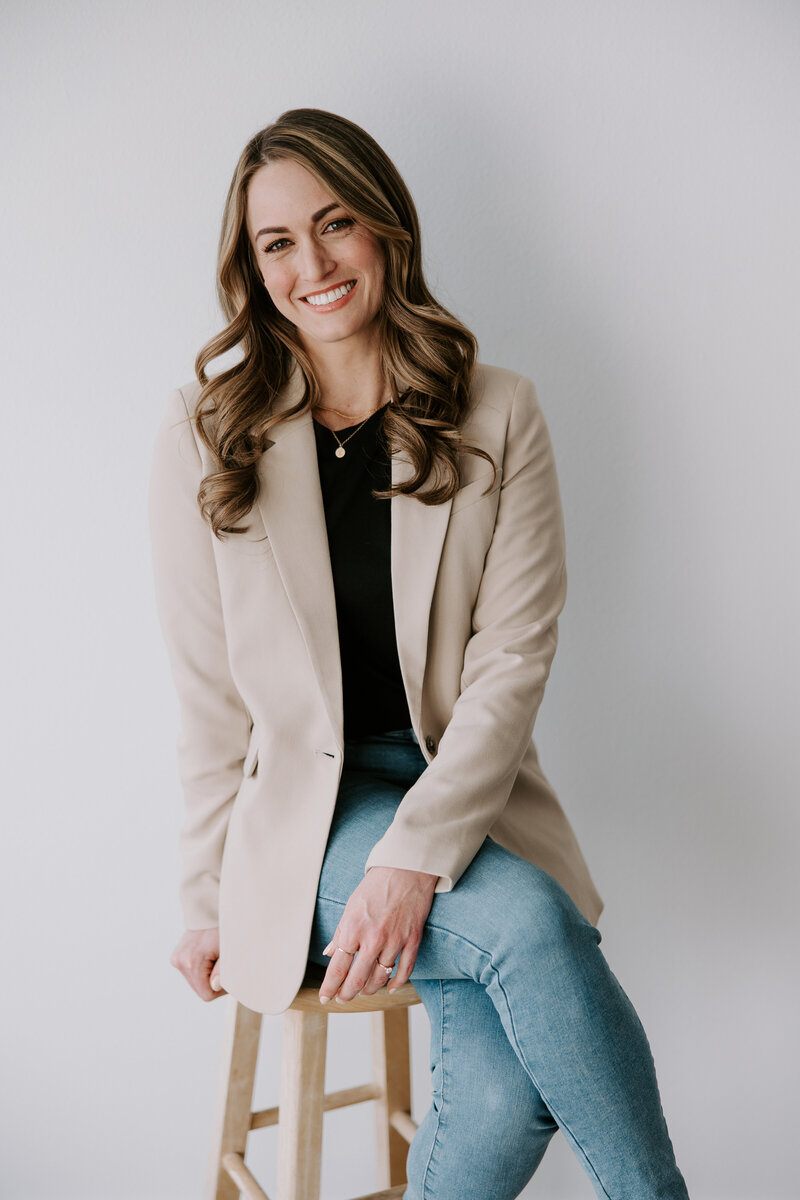 Portrait of website copywriter Erika Fitzgerald sitting on a wood stool
