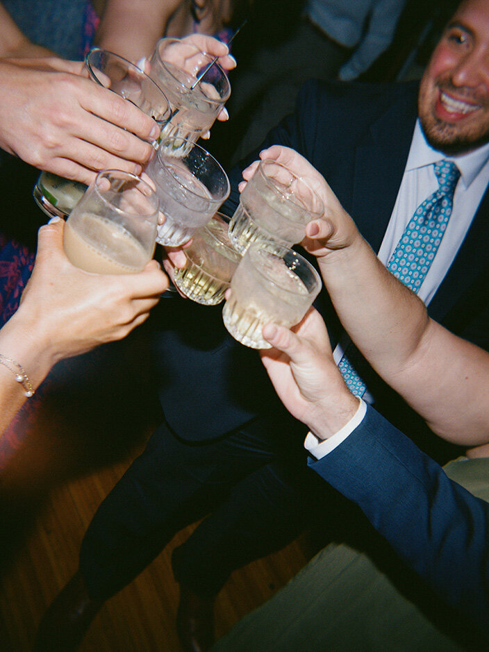 A group of people toasting with glasses at a Columbus wedding. Smiling faces and formal attire suggest a joyful and lively atmosphere.
