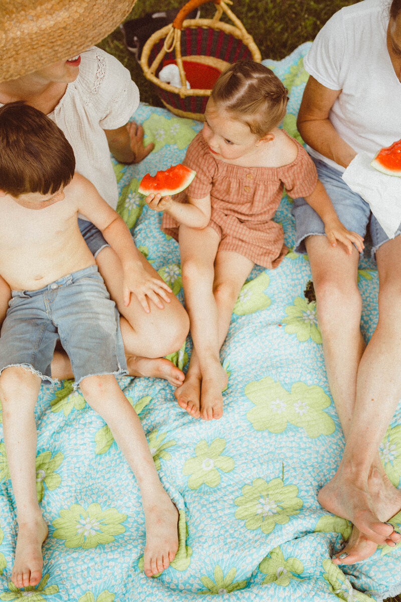 Family happily eating watermelon together during a fun summer photo session.