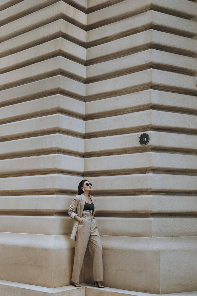 Brunette woman in a beige suit by beige building
