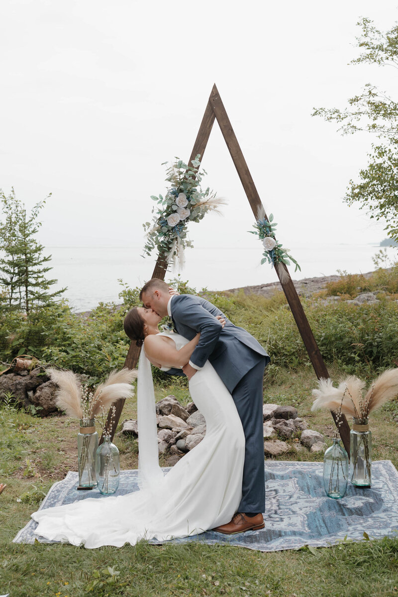 A person dipping their partner and kissing them during their wedding ceremony 