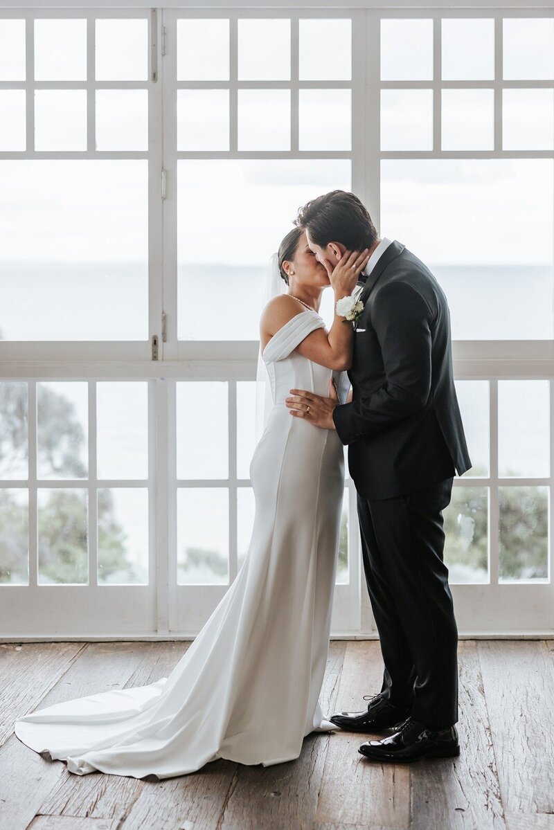 Bride and groom kissing at their micro wedding overlooking the ocean