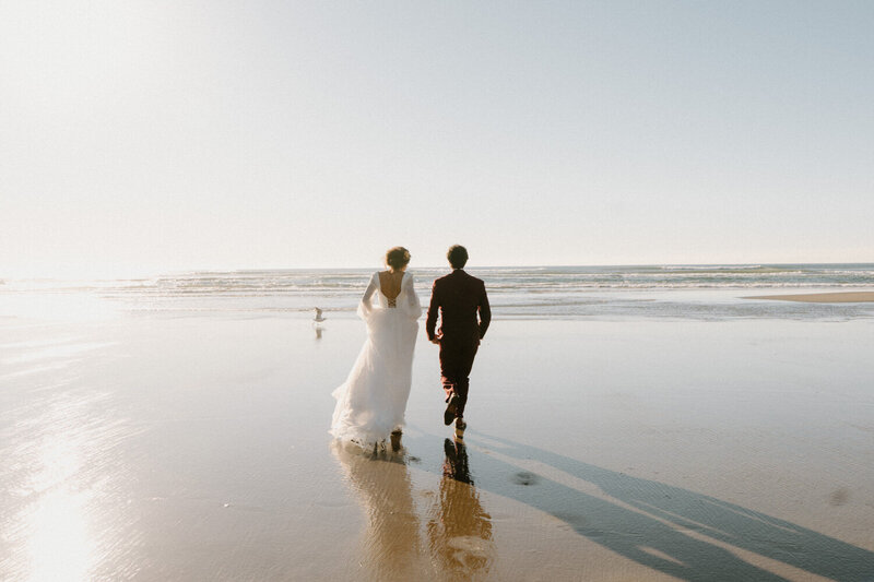 A couple stands in the grass against dramatic skies during their Cannon Beach elopement. 
