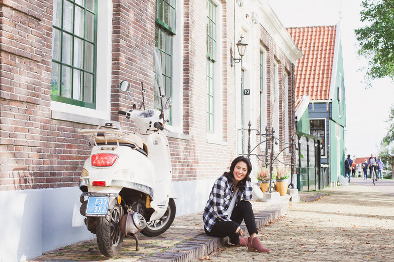 woman sitting on cobble street next to a moped
