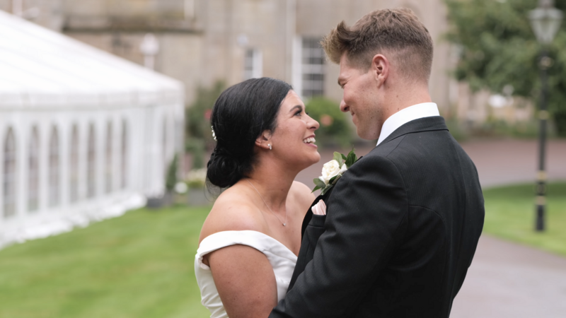 Couple looking at each other lovingly. Groom in suit, bride in white dress