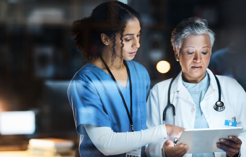 A nurse chatting with a doctor about documents.