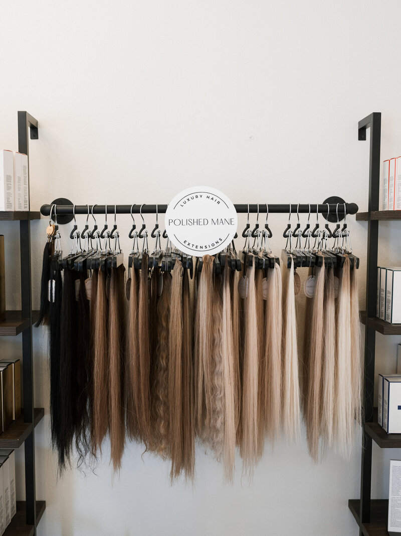hair extensions hanging on a rack in multiple colors