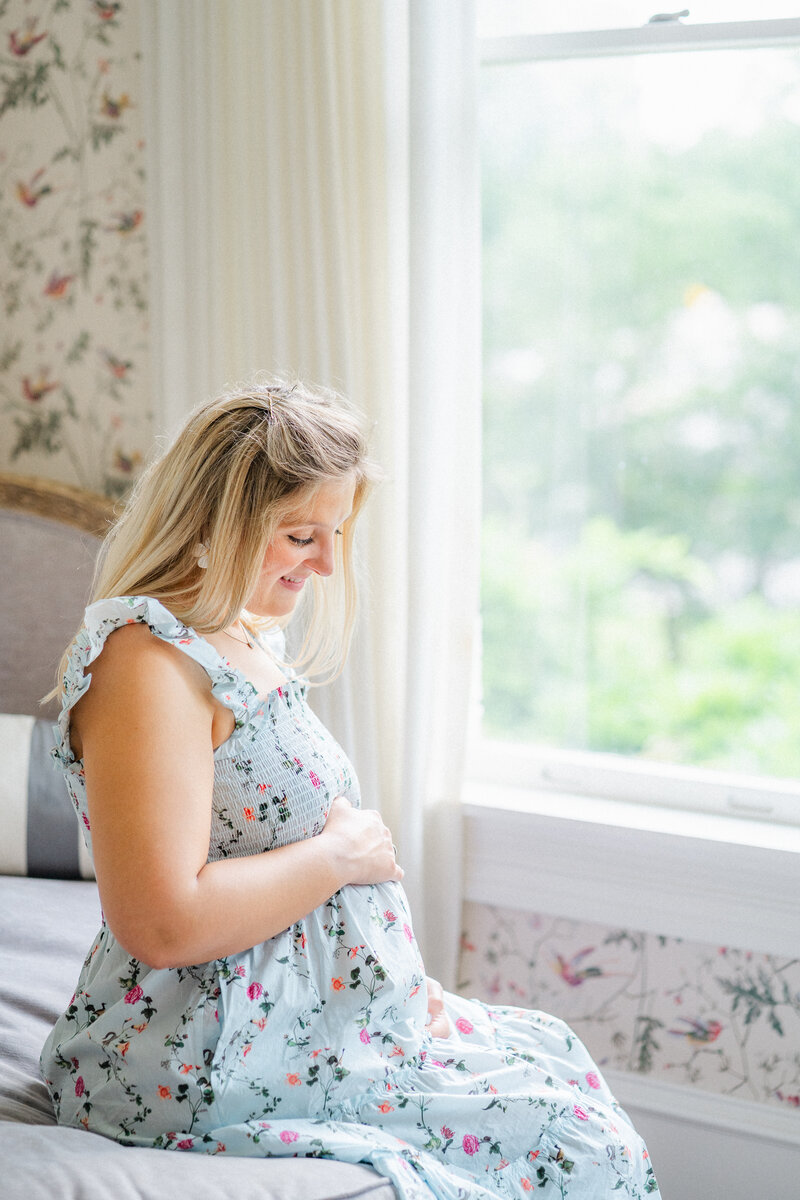 Austin, TX Family & Newborn Photography | An expectant mother sits on the edge of a daybed at Woodbine Mansion in Round Rock, TX.