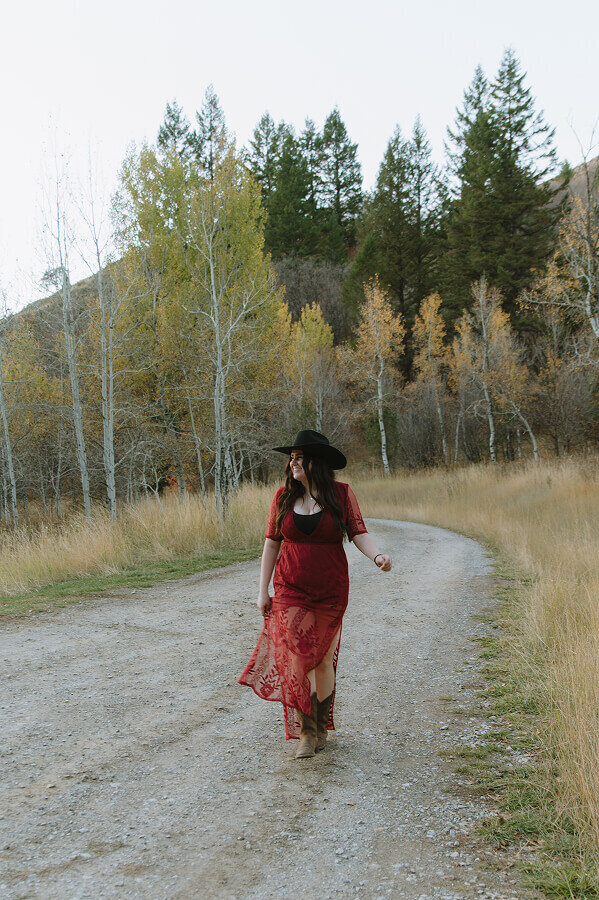 Looking off into the distance while walking towards the camera, a young woman smiles for a branding session portrait in Idaho Falls, ID.