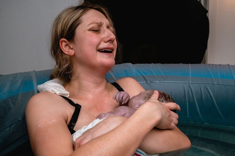 mother cries after birth holding her newborn