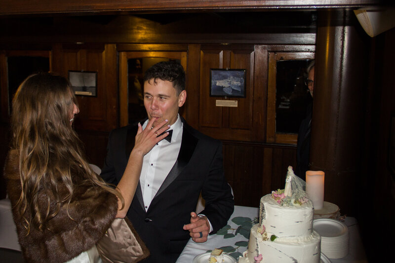 Bride feeding groom cake at wedding reception on boat | Wedding Photography Taken By Maine Wedding Photographer