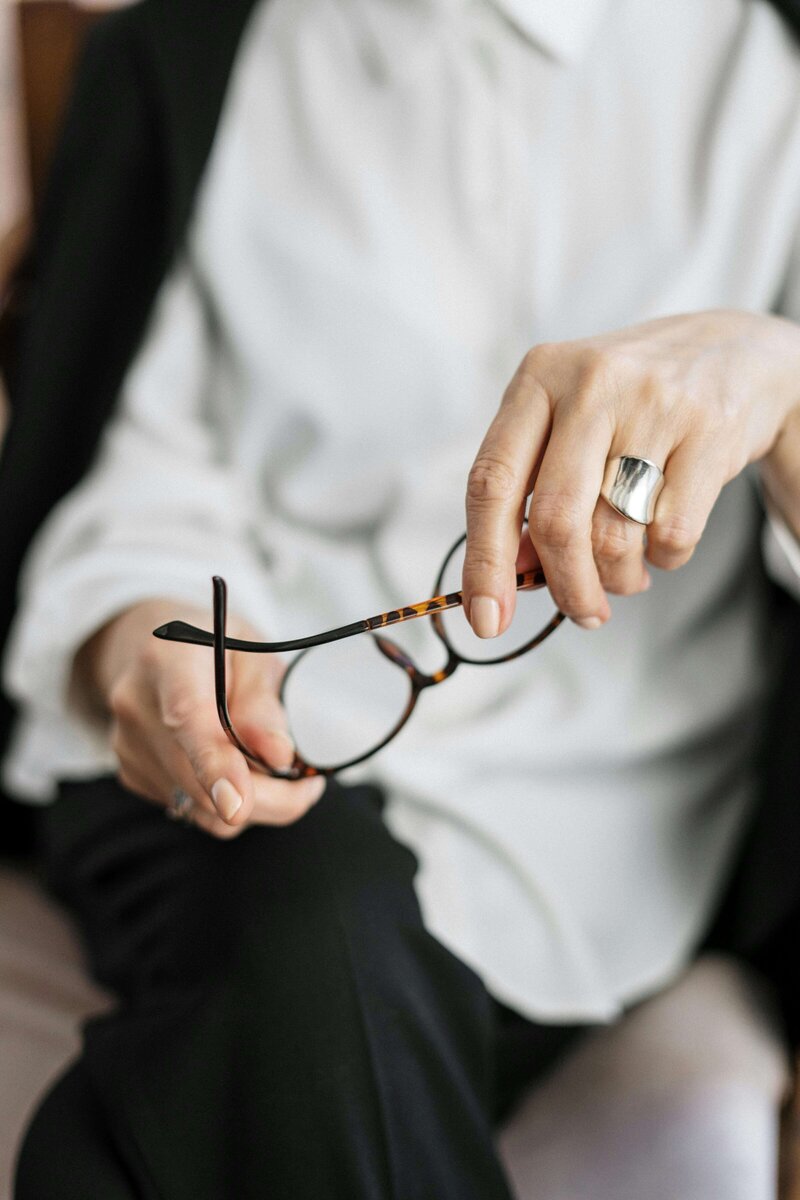 Close-up of therapist holding glasses in hand, representing reflection and presence