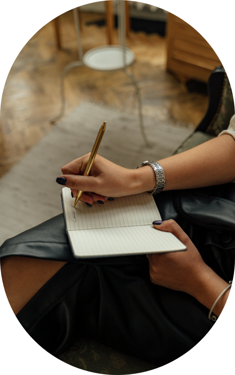 Close-up of a woman journaling while seated indoors, symbolizing emotional reflection and the process of healing through feminist therapy and self-awareness.
