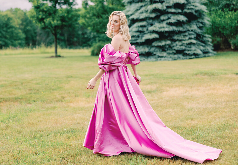 Woman walking through the grass in an elegant pink dress