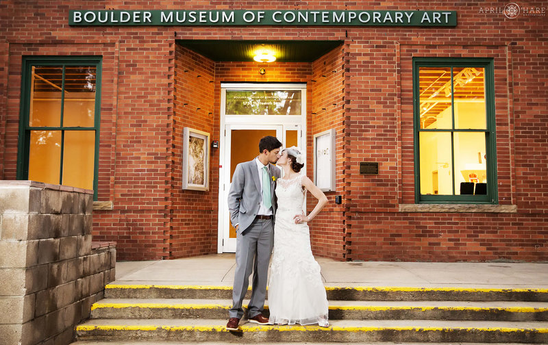Cute wedding couple kiss on the front steps of the historic Boulder Museum of Contemporary Art in Colorado