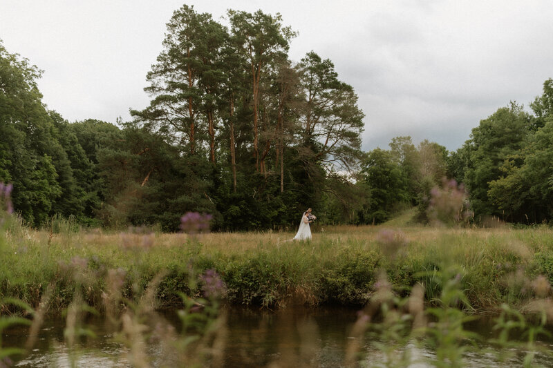 Bride and groom by lake captured by Jessica from Rainstorm Photo and Video
