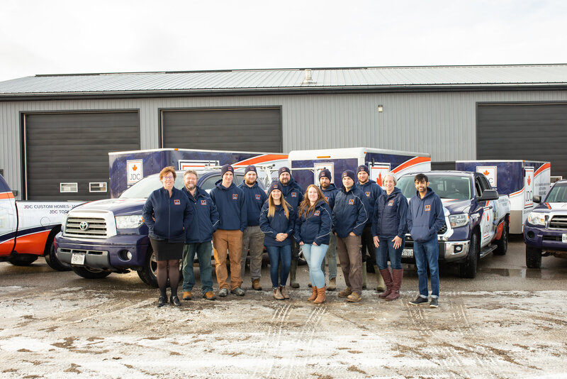 All JDC Custom Home staff in front of the trucks and a shop.