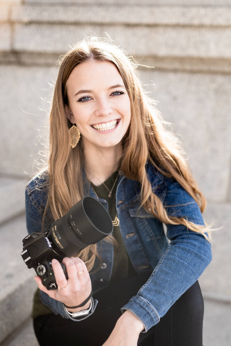 Young woman who is a photographer holding a camera and smiling