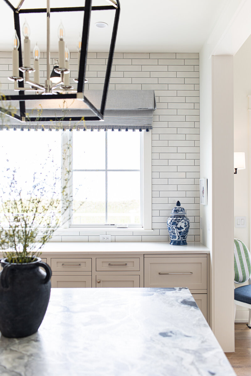 A beautifully styled kitchen window featuring built-in cabinets, tiled walls, and exquisite furnishings. The editorial shot captures the elegance and functionality of the space, highlighting the attention to detail in the design.