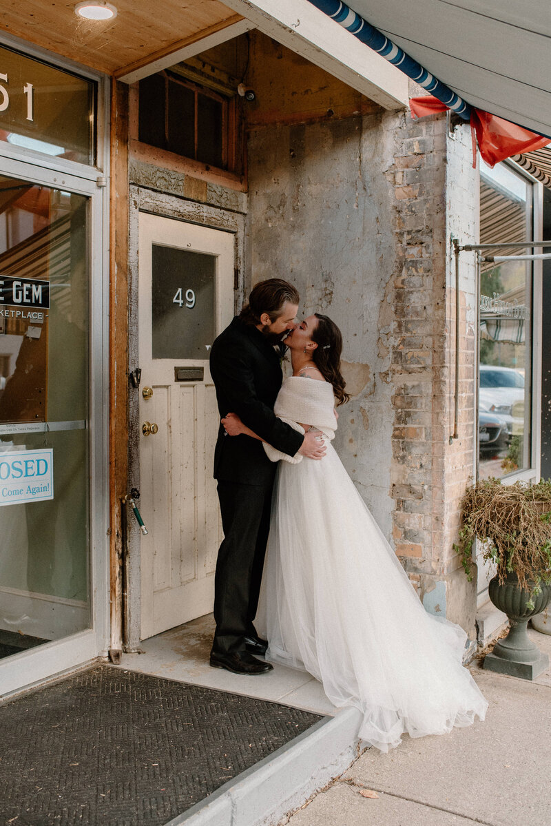 bride and groom kiss in front of store in paris, ontario