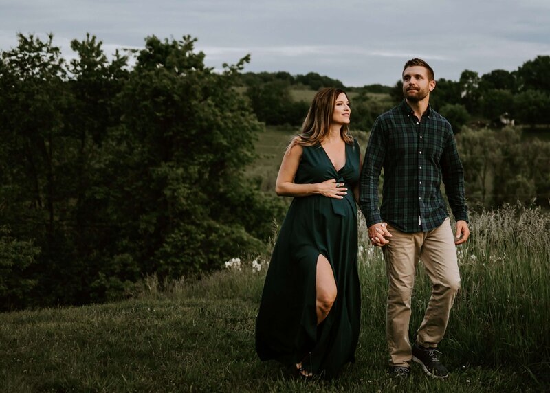 A couple walking through a field during their maternity session with their Pittsburgh maternity photographer.