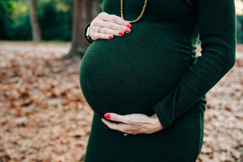 closeup of woman holding pregnant belly in green dress by Raleigh Maternity Photographer
