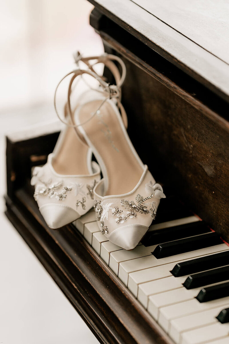 An artistic detail shot from an Atlanta wedding, featuring the bride's beautiful shoes on a vintage piano, by a creative wedding photojournalist