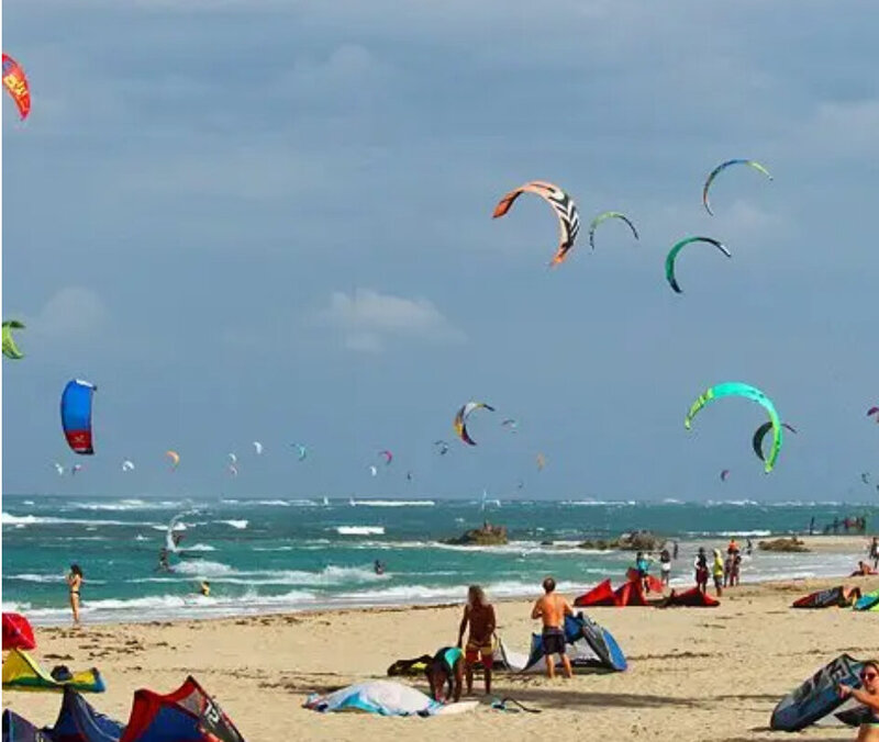 Crowded beach with kite surfers in action along the Dominican coastline near Cabarete