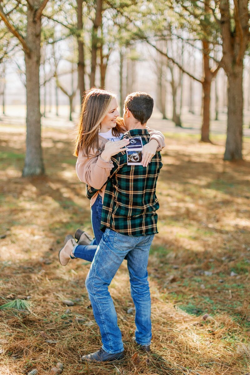 a man and woman hugging while holding ultrasound pictures