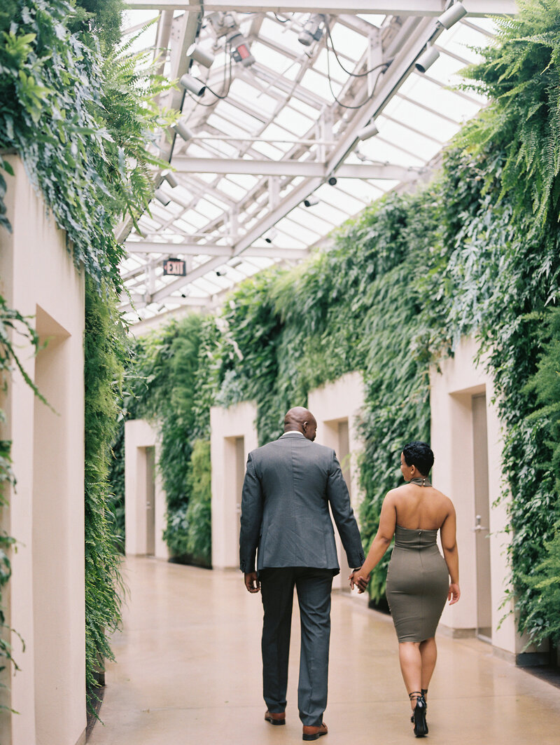 couple walking down fern hallway
