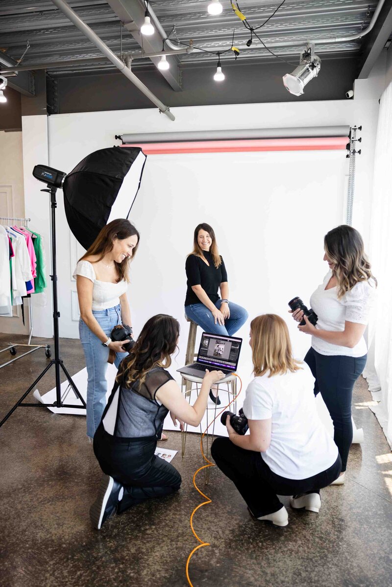 Behind the scenes of brand photoshoot showing creative team collaborating in studio with professional lighting setup and wardrobe styling