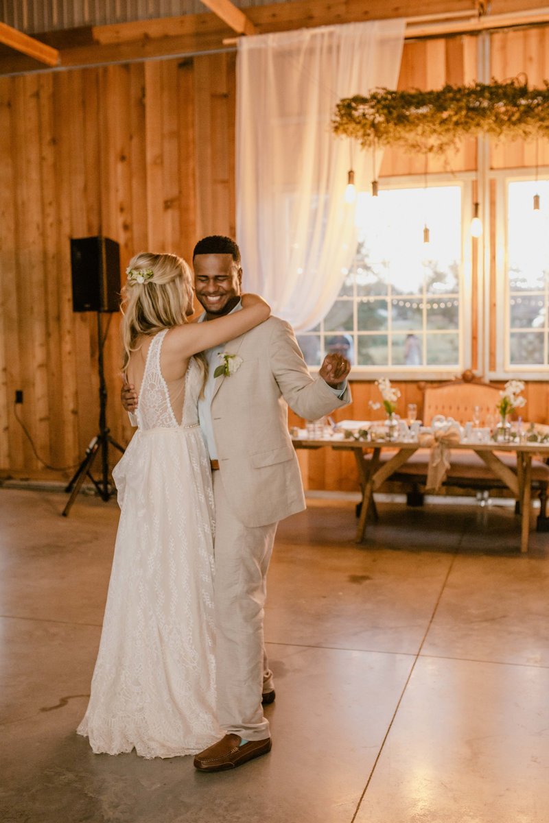 Bride and groom dancing their first dance at their reception. Groom is smiling and snapping his fingers to the music.