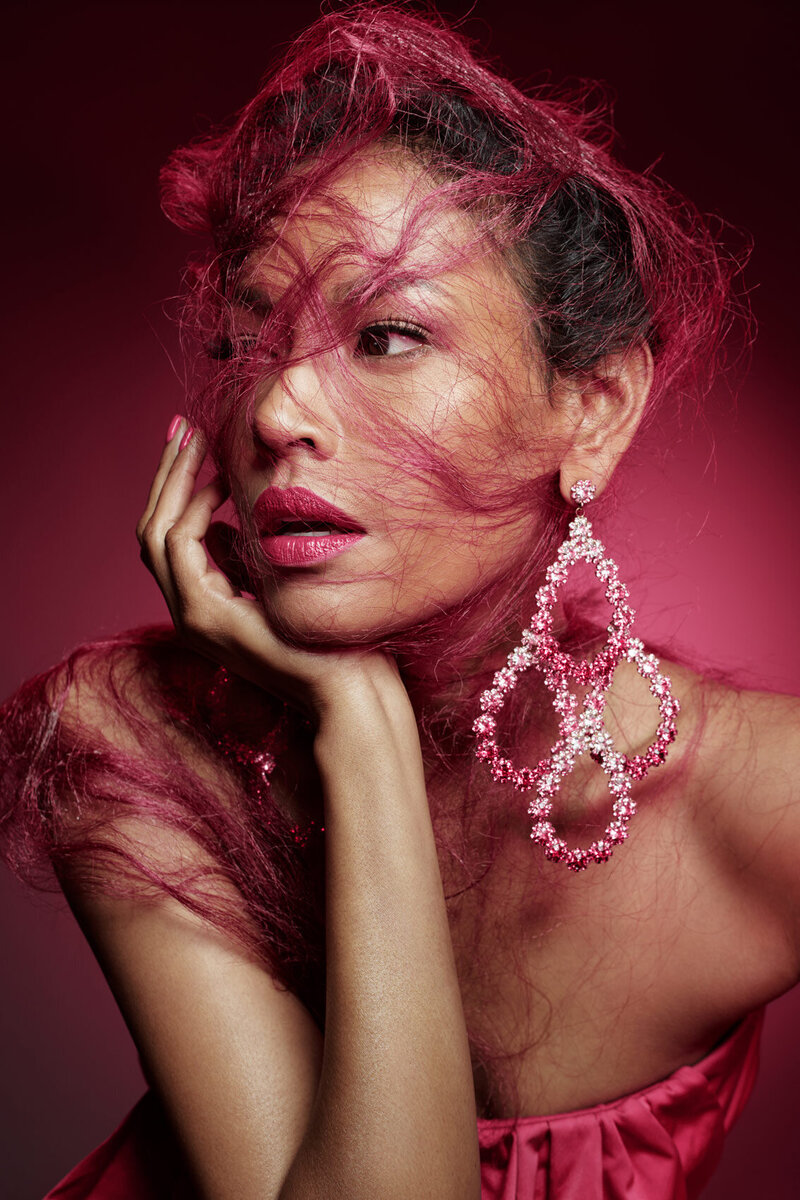 Dramatic portrait of Amira with pink floral accents and vibrant makeup, captured by Ylva Erevall.