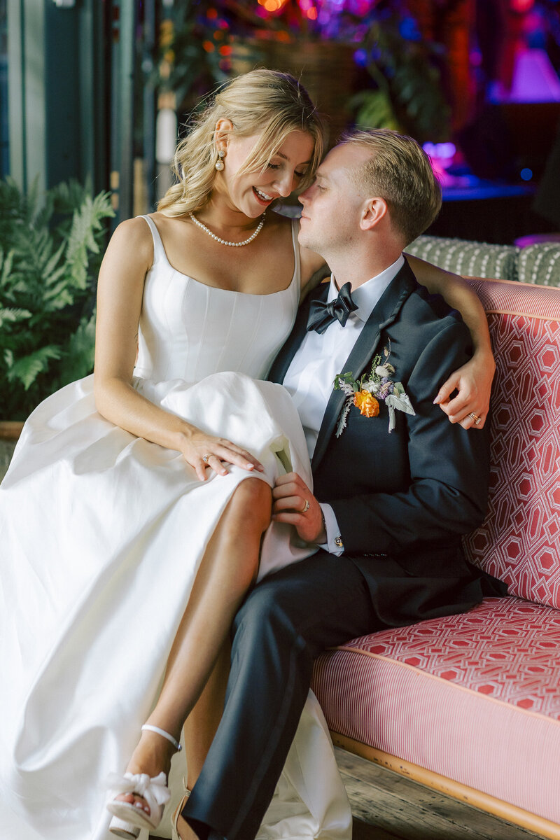 Couple on the couch with florals behind them, wedding attire, black and white