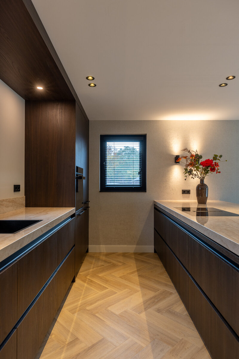 Keukenoopstelling met warme materialen en symmetrie zorgen voor een tijdloze, luxe uitstraling met een natuurlijke lichtinval.