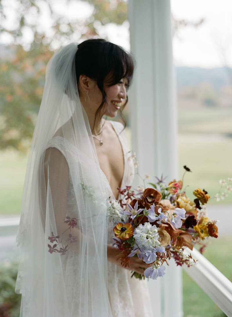 Organic artistic bridal bouquet with delicate blooms and texture. Fall bridal bouquet for private home wedding featuring orchids, ranunculus, and sweet peas. Textural bridal bouquet in a tasteful fall pallet of copper, lavender, gold, and ruby. Private property autumnal wedding in the hills of Tennessee. Design by Rosemary & Finch Floral Design in Nashville, TN. 