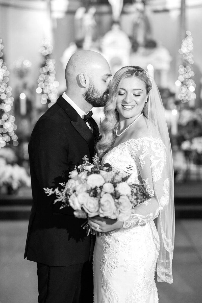 Close up of bride cupping her groom's face and smiling at camera