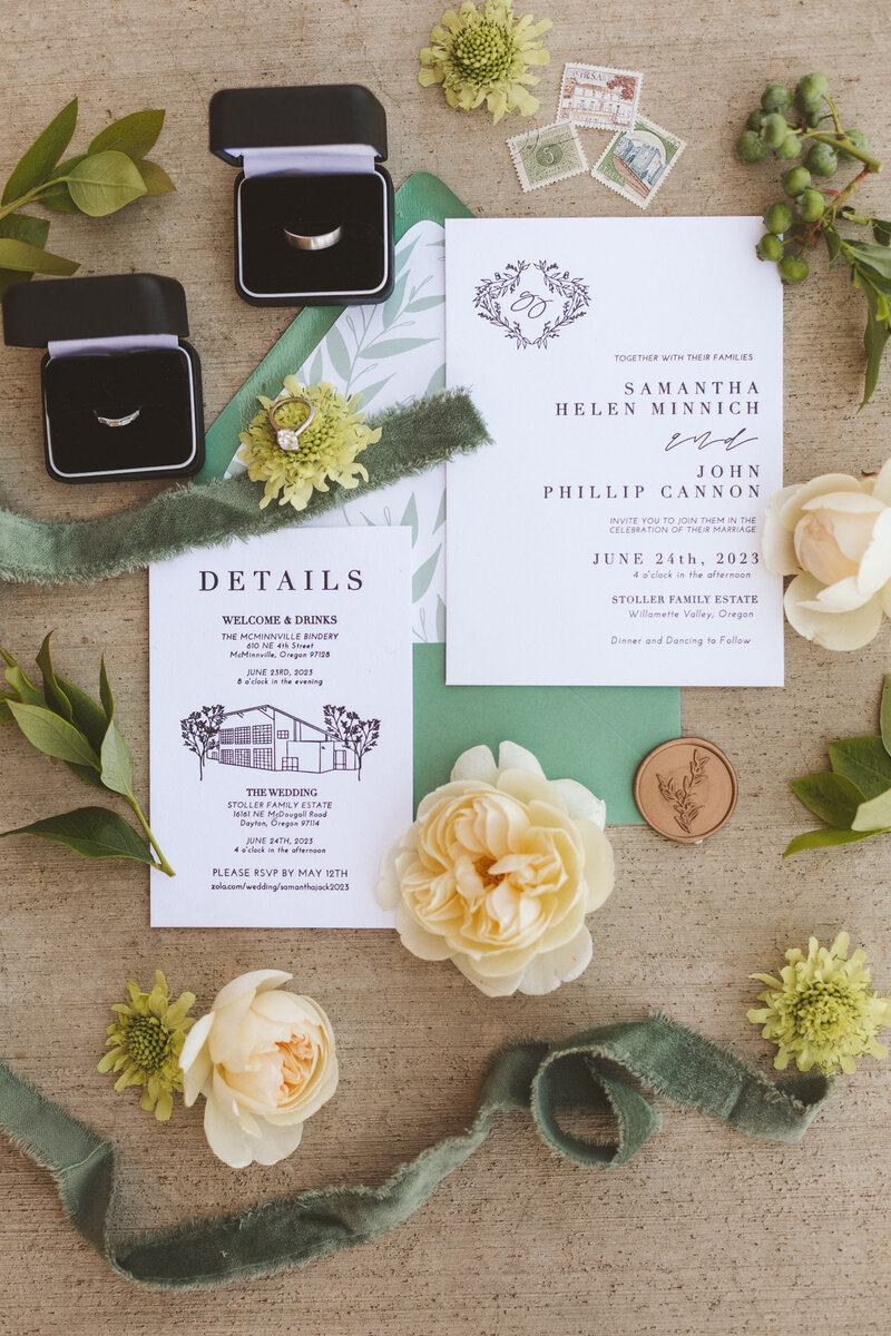 A flat lay with flowers, wedding ring, and wedding invitations with customized calligraphy by Life in Letters.