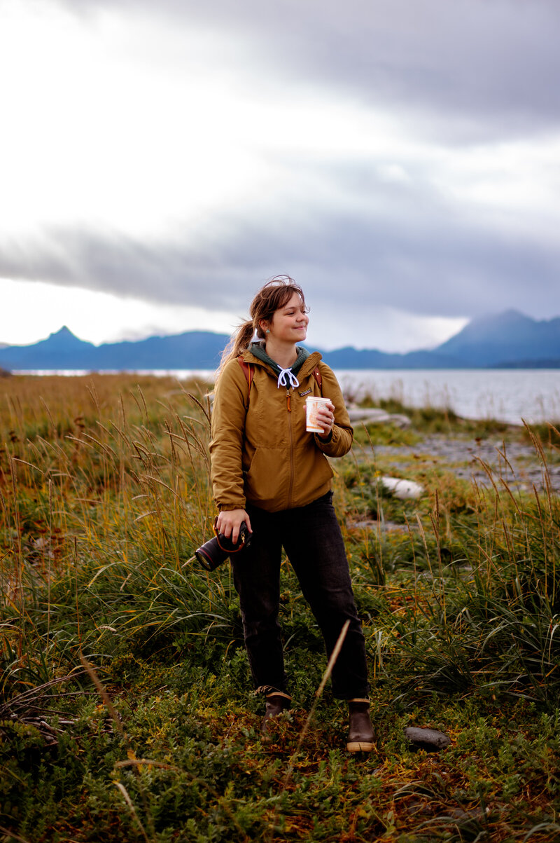 Alaska photographer  holding her camera and a coffee