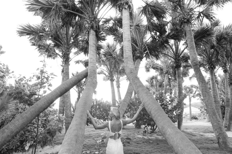 blonde woman surrounded by palm trees in the Caribbean