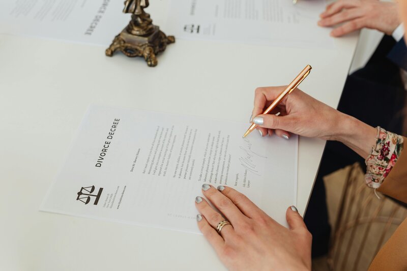 Hands signing formal documents with a gold pen on a white table, representing payroll processing or employee onboarding paperwork

