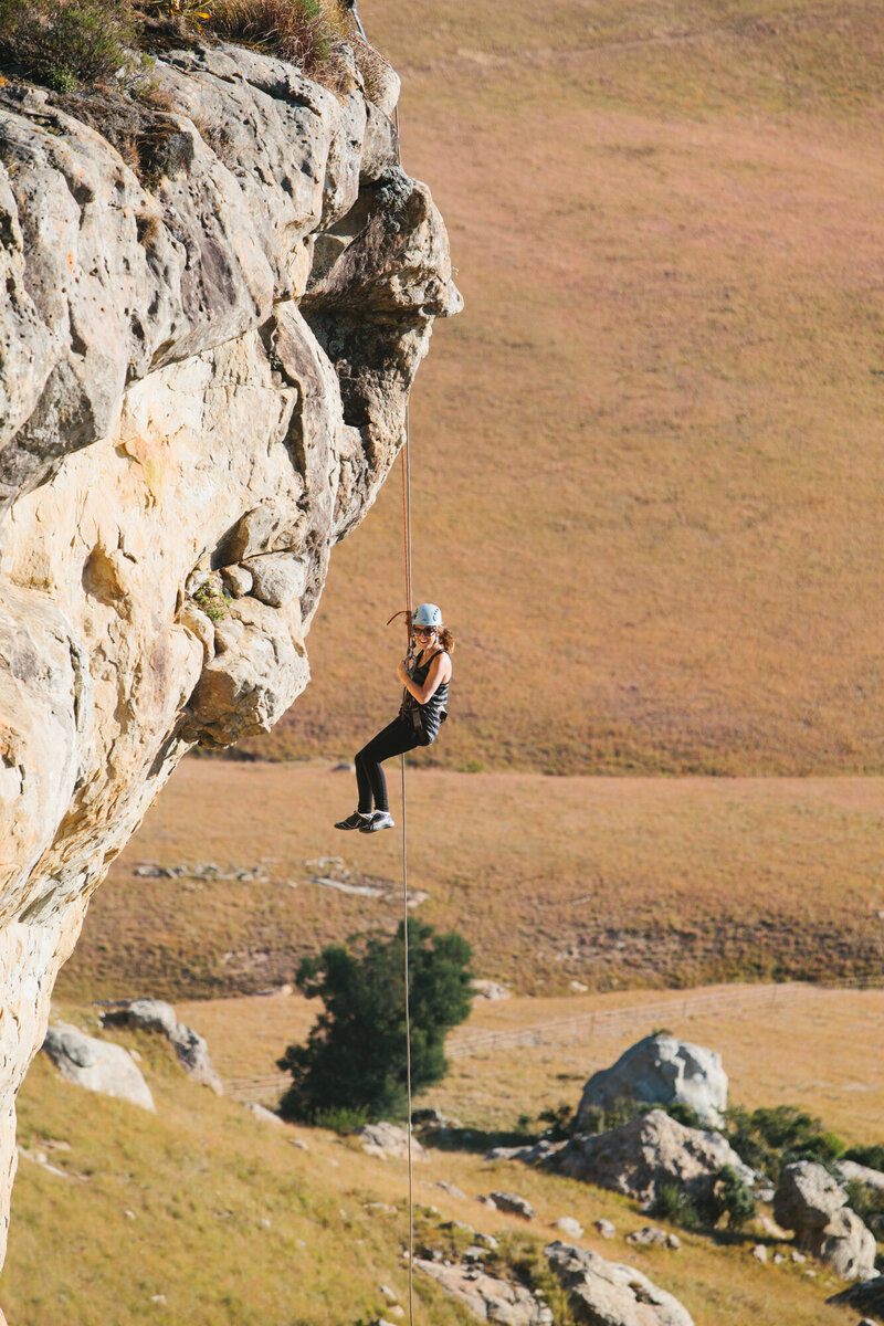 woman repelling from cliff