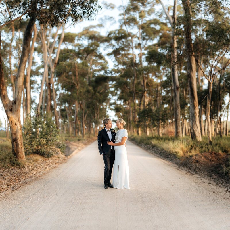 A wedding photo captures a bride and groom taking a moment out on a gravel road
